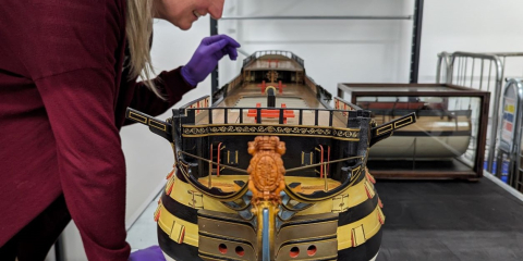 A scale-model of HMS Victory is examined by Principal Curator Victoria Ingles